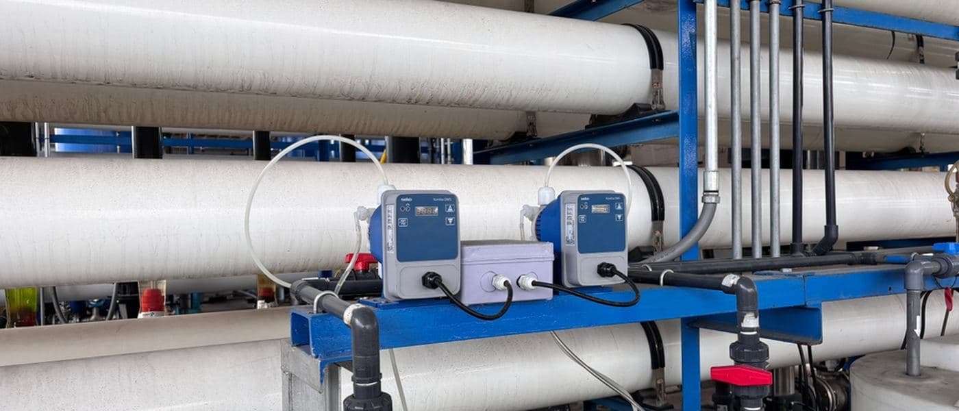 Chemical dosing pumps feeding liquid into industrial treatment pipework.